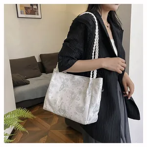 Close-up of white canvas tote bag featuring butterfly print and woven rope handle