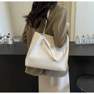 Détail d'un sac cabas en cuir mat blanc avec pli latéral et longue bandoulière de mode