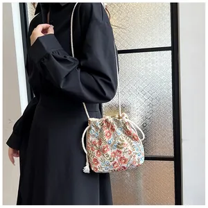 Detail of floral drawstring bucket bag with colorful patterns and woven shoulder strap