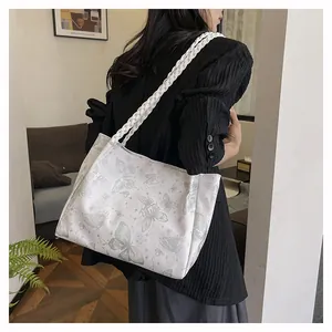 Close-up of white butterfly print tote bag with woven shoulder straps on a casual model