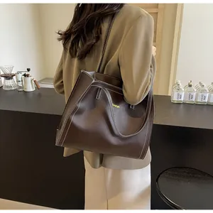Détail d'un cabas en cuir marron foncé avec surpiqûres blanches pour le trajet quotidien
