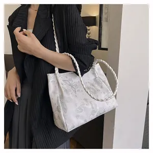 Detail of white tote bag with butterfly prints and textured woven handles on a model