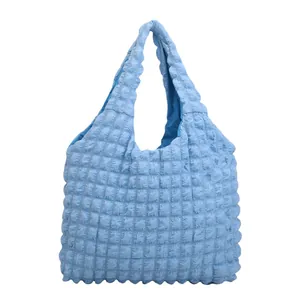 Light blue pleated tote bag with bubble quilted texture and seamless handles on white backdrop