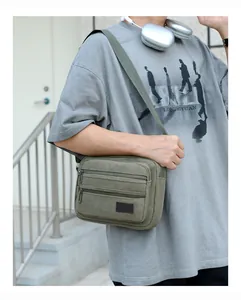 Detail view of khaki green canvas crossbody bag featuring three zippered compartments