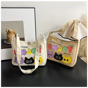 Dettaglio borse a tracolla in tela beige e marrone con stampe di gatti e chiusura lampo
