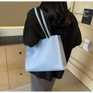 Détail macro du sac cabas en cuir PU bleu clair avec surpiqûres et logo métallique