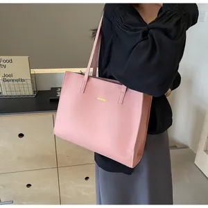 Gros plan d'un sac cabas en cuir rose avec logo doré porté par un mannequin