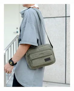 Detail of army green canvas crossbody bag with multiple zippers and adjustable strap