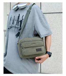 Detailed side view of military green canvas crossbody bag with multiple zip pockets