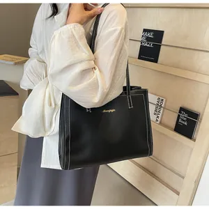 Détail du sac cabas en cuir noir avec surpiqûres blanches et logo doré élégant