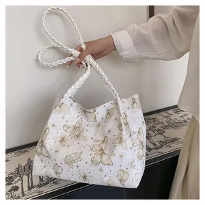 Close-up of white tote bag with butterfly patterns and woven handle detail