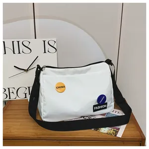 Detalle de bolso bandolera de lona blanca con correa ajustable y parches de moda