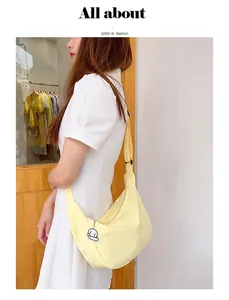 Close-up of crescent canvas bag in light yellow with a cute puppy keychain