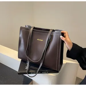 Détail d'un cabas marron foncé avec surpiqûres blanches contrastées et longues anses