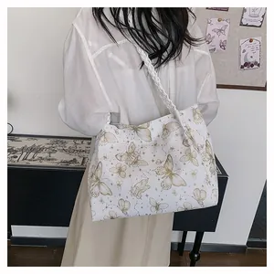 Detail of white canvas tote bag featuring brown butterfly prints and woven rope handles