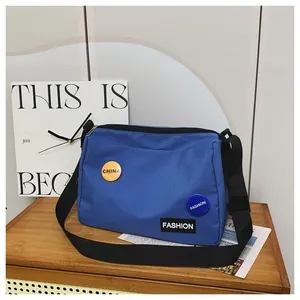 Detalle de bandolera de lona azul con parches de moda y correa negra ajustable