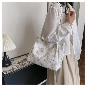 Detail shot of white tote bag featuring golden butterfly prints and woven handles