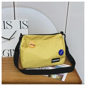Detalle de un bolso bandolera de lona amarillo vibrante con insignias y correa ajustable