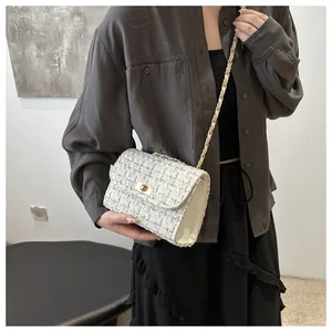 Détail du sac bandoulière en tweed avec fermoir doré et bandoulière chaîne sur modèle