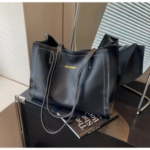 Détail du sac cabas en cuir PU noir avec surpiqûres blanches et logo doré