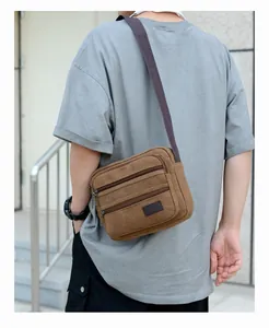 Brown canvas crossbody bag for men featuring multiple zipper pockets and sport label