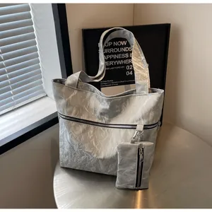 Close-up of silver tote bag with crinkled texture, zipper detail and matching pouch