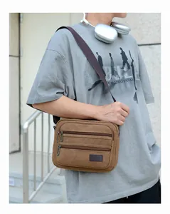 Detail of a brown canvas crossbody bag with multi-zipper pockets for men's casual use