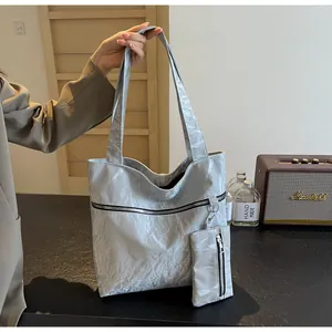 Detail view of silver textured tote bag with pleated finish and matching mini pouch