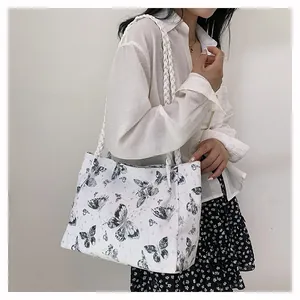 Detail of white canvas tote bag with butterfly prints and woven rope handle straps