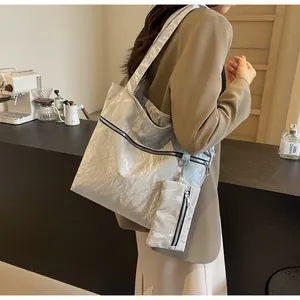 Detail of silver metallic tote bag with matching mini pouch in minimalist cafe setting