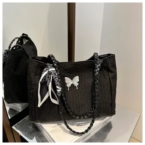 Detail of black pleated tote bag featuring silver butterfly charm and patterned silk scarf
