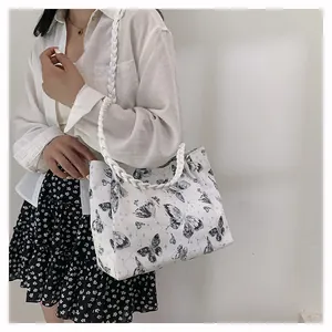 Detailed view of large white tote bag featuring black butterfly prints and woven handles
