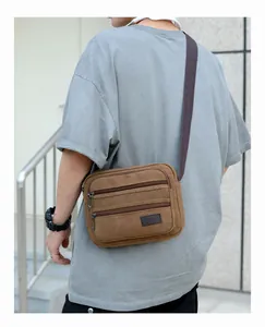Detailed view of durable brown canvas crossbody bag featuring multi-zipper compartments