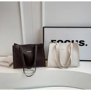 Détail de cabas café et beige avec coutures fines et détails de logo doré élégant