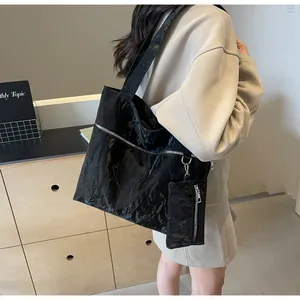 Detail of black pleated faux leather tote bag with matching mini pouch on shoulder