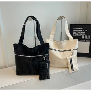 Detail of glossy wrinkled texture tote bags in black and cream with matching pouches
