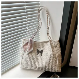 Detailed macro view of woven handles and decorative scarf on a cream butterfly tote bag