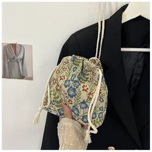 Detailed close-up of floral jacquard canvas bucket bag with drawstring and tassel detail