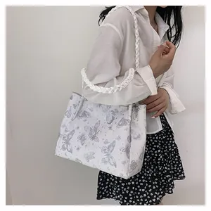 White tote bag with grey butterfly prints and woven rope handles shown on a model