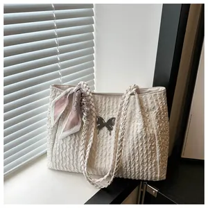 Detail of off-white pleated tote bag with woven handles and a decorative silk scarf