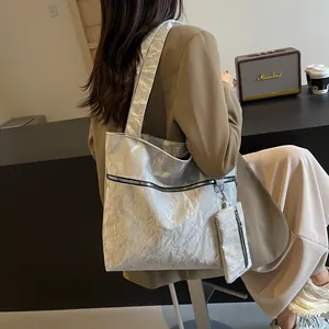 Silver metallic pleated tote bag with matching coin purse shown on shoulder in street style