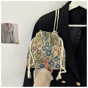 Detail of floral tapestry drawstring bag showing woven texture and cotton tassels