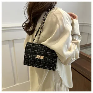 Détail du sac bandoulière en tweed noir avec chaîne dorée porté par un mannequin femme