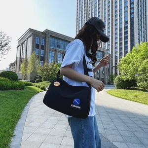 Bolso bandolera grande de lona negra con parches de moda en un entorno urbano exterior