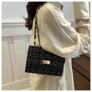 Gros plan sur la texture en tweed noir et blanc et la chaîne dorée de ce sac à main