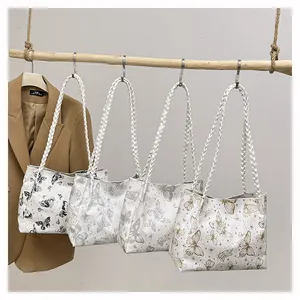 Detail of four butterfly print tote bags with woven rope handles hanging on a wooden pole