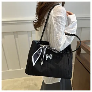 Detail of black pleated tote bag with silver butterfly buckle and decorative silk scarf