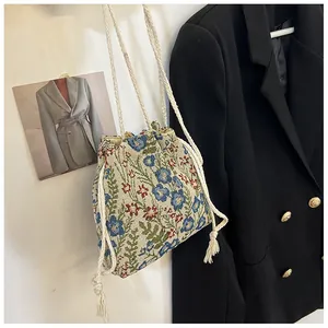 Detail of floral jacquard bucket bag featuring woven drawstring and tassel accents