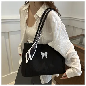 Detail of black pleated tote bag featuring white butterfly accessory and patterned silk scarf