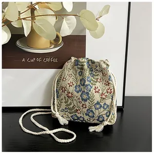 Detailed close-up of vintage floral jacquard fabric and woven drawstring strap on bucket bag